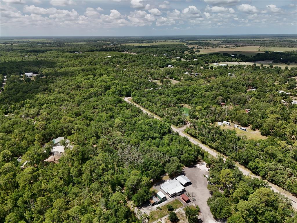 An aerial view shows a rural property with multiple buildings surrounded by dense forest — SW GATOR TRAIL, ARCADIA, FL