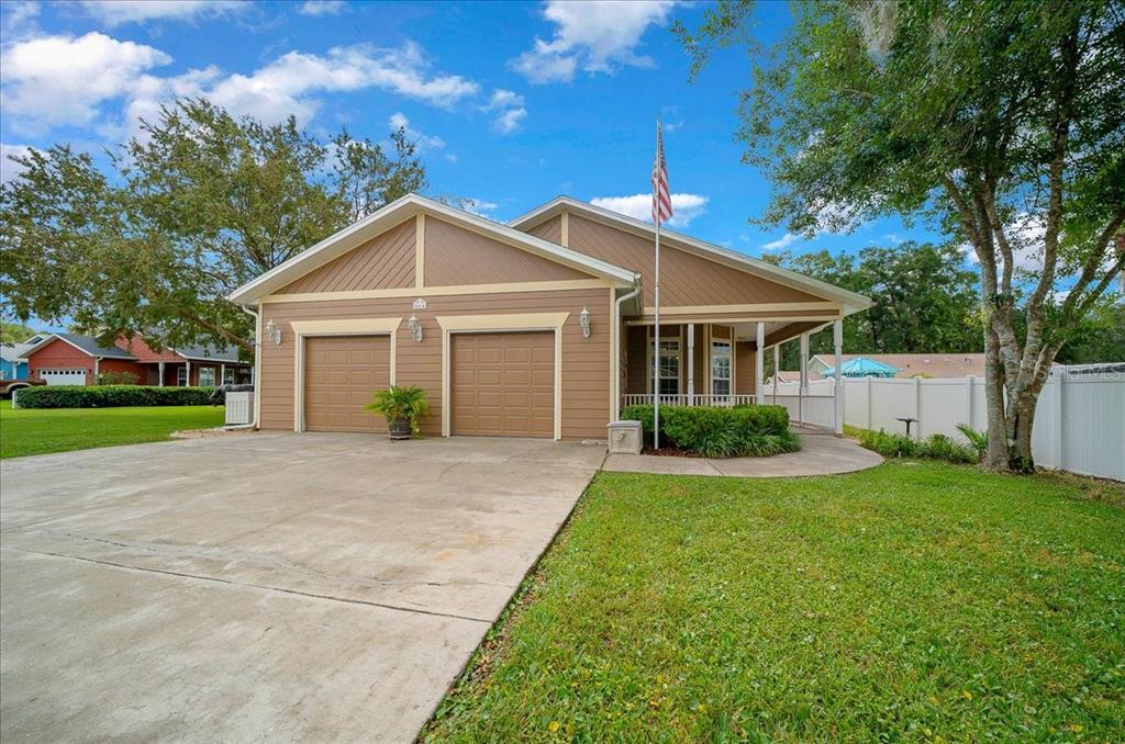 A tan house with a two-car garage, a front porch, and an American flag pole — 4014 NE 23RD PLACE, OCALA, FL