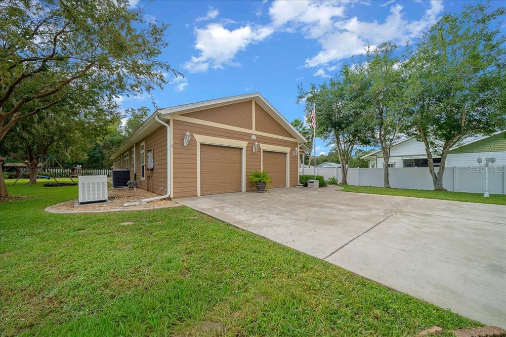 A detached two-car garage with tan siding sits on a concrete driveway in a yard — 4014 NE 23RD PLACE, OCALA, FL