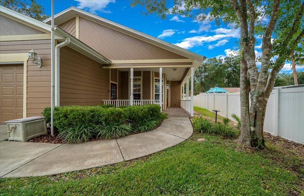 A tan house with a covered porch, a concrete walkway, and a white vinyl fence — 4014 NE 23RD PLACE, OCALA, FL