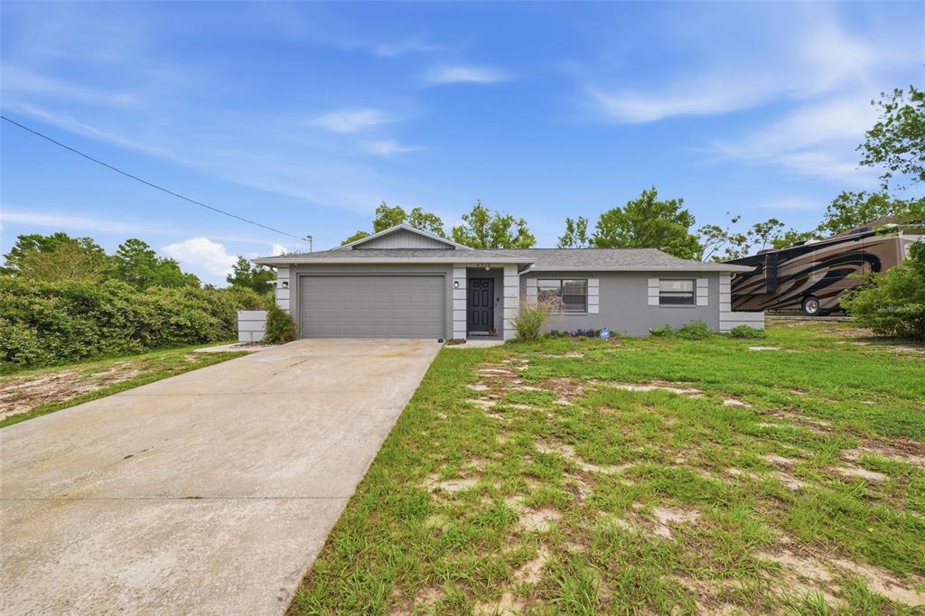 A single-story gray house with a two-car garage and a concrete driveway — 6310 GAINSBORO AVENUE, SPRING HILL, FL