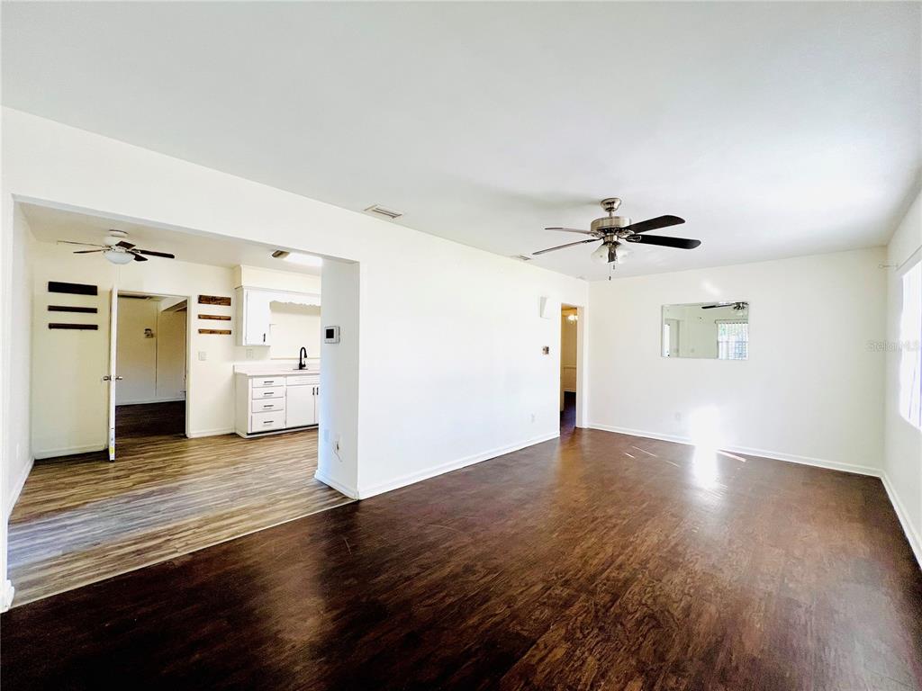 A living room with dark wood floors connects to a kitchen with white cabinetry — 501 AVENUE G SE UNIT A, WINTER HAVEN, FL