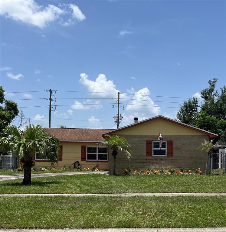 A yellow house exterior features an orange garage door, matching front door, and brown shutters — 586 TULANE DRIVE, ALTAMONTE SPRINGS, FL