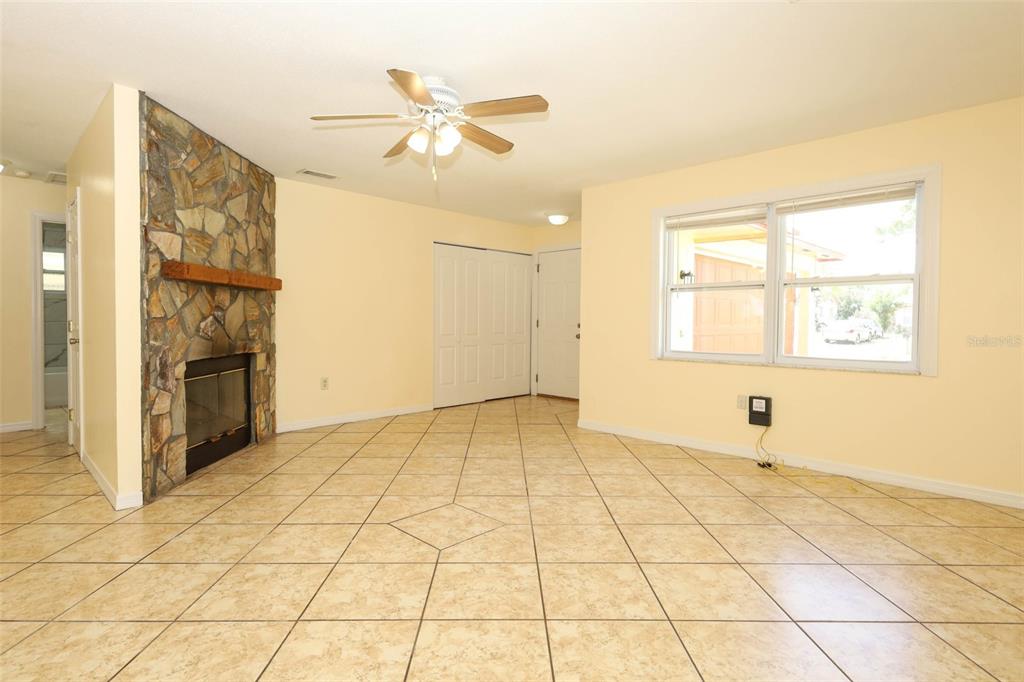 A living room features light yellow walls, beige tile flooring, a stone fireplace, and a ceiling fan — 586 TULANE DRIVE, ALTAMONTE SPRINGS, FL