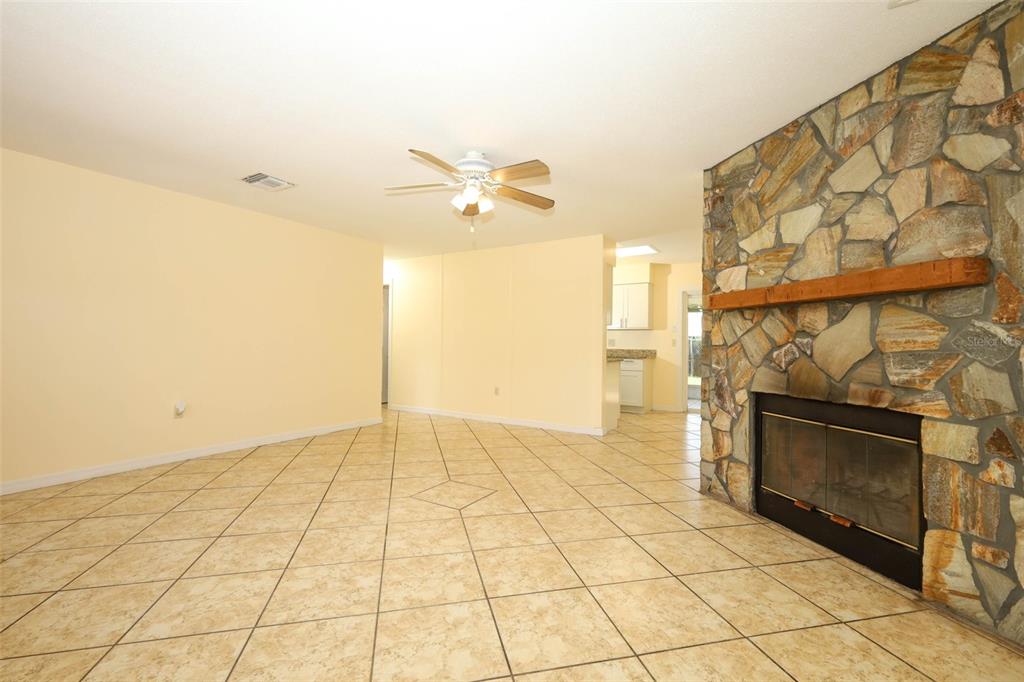 A living room with light-colored tile flooring, a stone fireplace, and a ceiling fan — 586 TULANE DRIVE, ALTAMONTE SPRINGS, FL