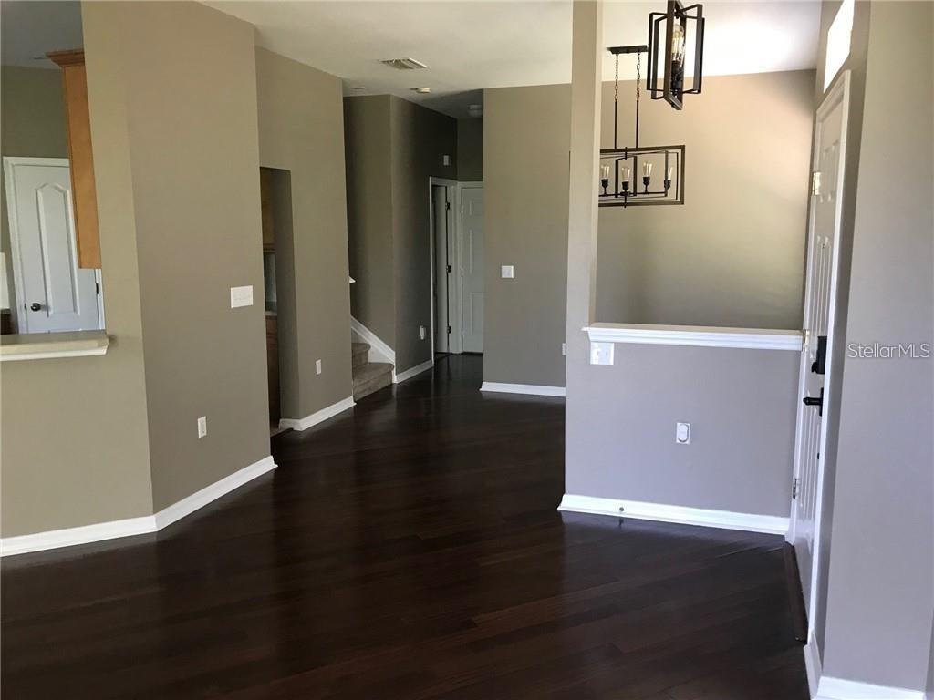 An entryway with dark hardwood floors leads to a staircase and a dining area — 7542 RED MILL CIRCLE, NEW PORT RICHEY, FL