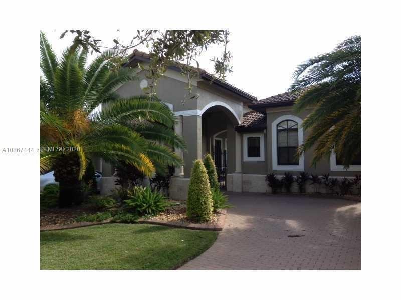 A beige house with a tiled roof features a paved driveway and palm trees — 19080 SW 24th Street, Miramar FL 33029, MIRAMAR, FL