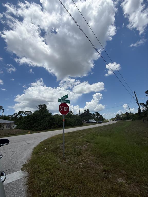 A stop sign stands at a street intersection under a bright, cloudy blue sky — 12526 RATHWELL AVENUE, PORT CHARLOTTE, FL