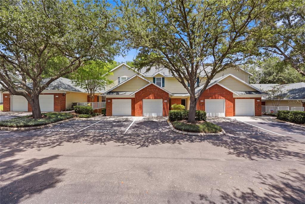 A row of attached townhomes with brick facades, white garage doors, and mature shade trees — 13200 W NEWBERRY ROAD UNIT F-29, NEWBERRY, FL