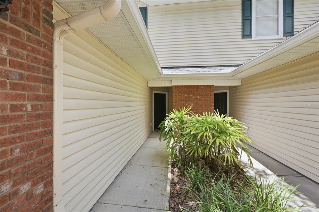 An exterior view of a building entrance with two doors, beige siding, and a plant — 13200 W NEWBERRY ROAD UNIT F-29, NEWBERRY, FL