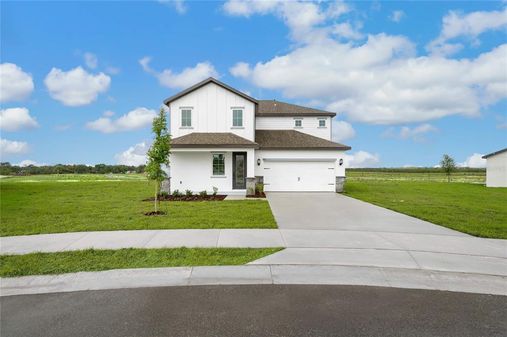 A two-story white house with a two-car garage sits on a grassy suburban lot — 806 PONKAN COURT, BABSON PARK, FL