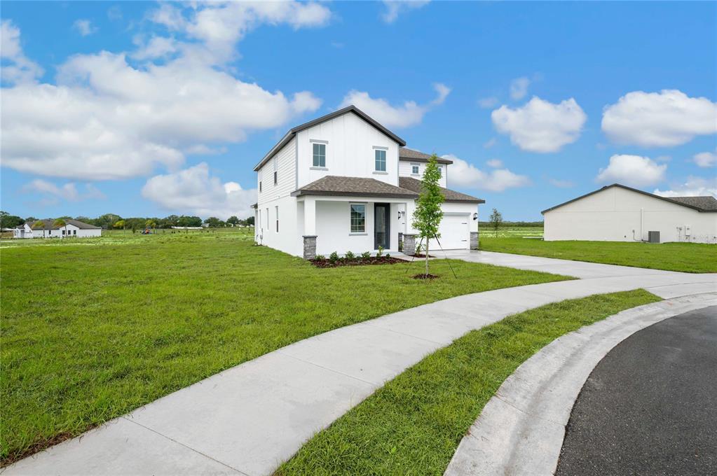 A two-story white house with a front porch and attached garage sits on a lawn — 806 PONKAN COURT, BABSON PARK, FL