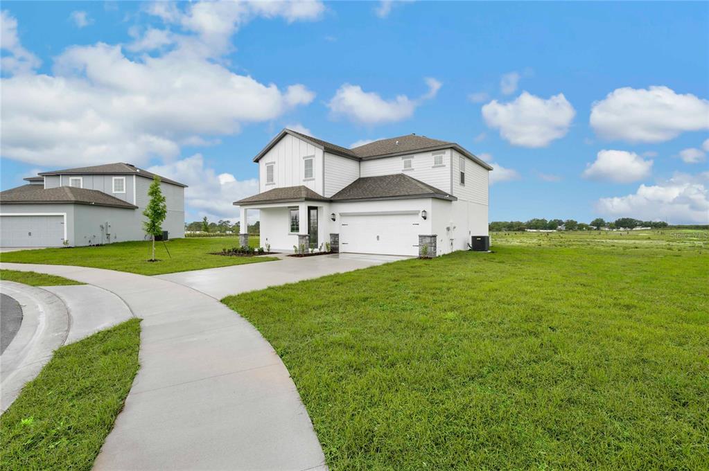 A two-story white house with a two-car garage sits on a grassy corner lot — 806 PONKAN COURT, BABSON PARK, FL
