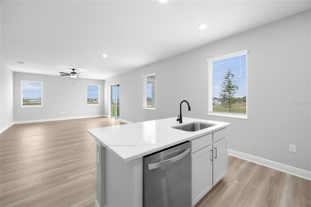 A kitchen island with a sink and dishwasher sits in a room with light flooring — 806 PONKAN COURT, BABSON PARK, FL