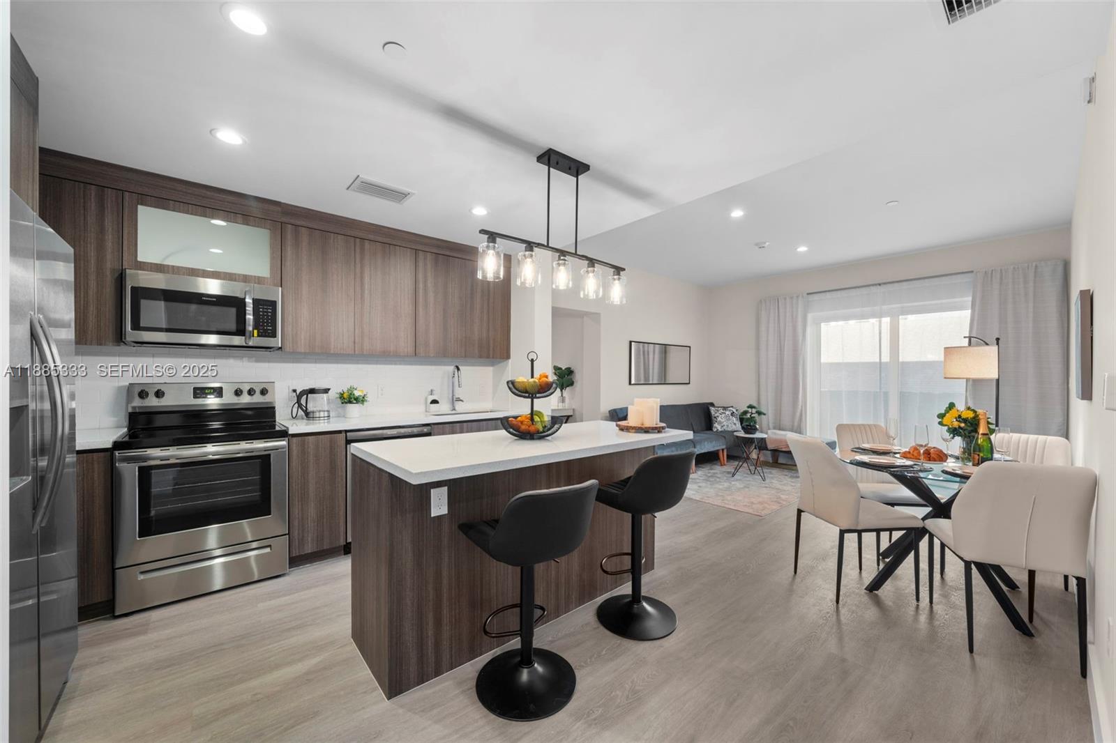 A modern kitchen with wood cabinets, stainless steel appliances, and an island with bar stools — 1938 Jackson St # 306, Hollywood FL 33020, HOLLYWOOD, FL