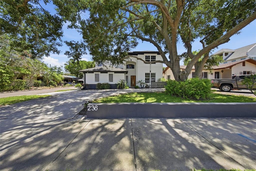 A two-story white house with a dark trim sits behind a low gray wall — 236 15TH AVENUE SE, ST PETERSBURG, FL