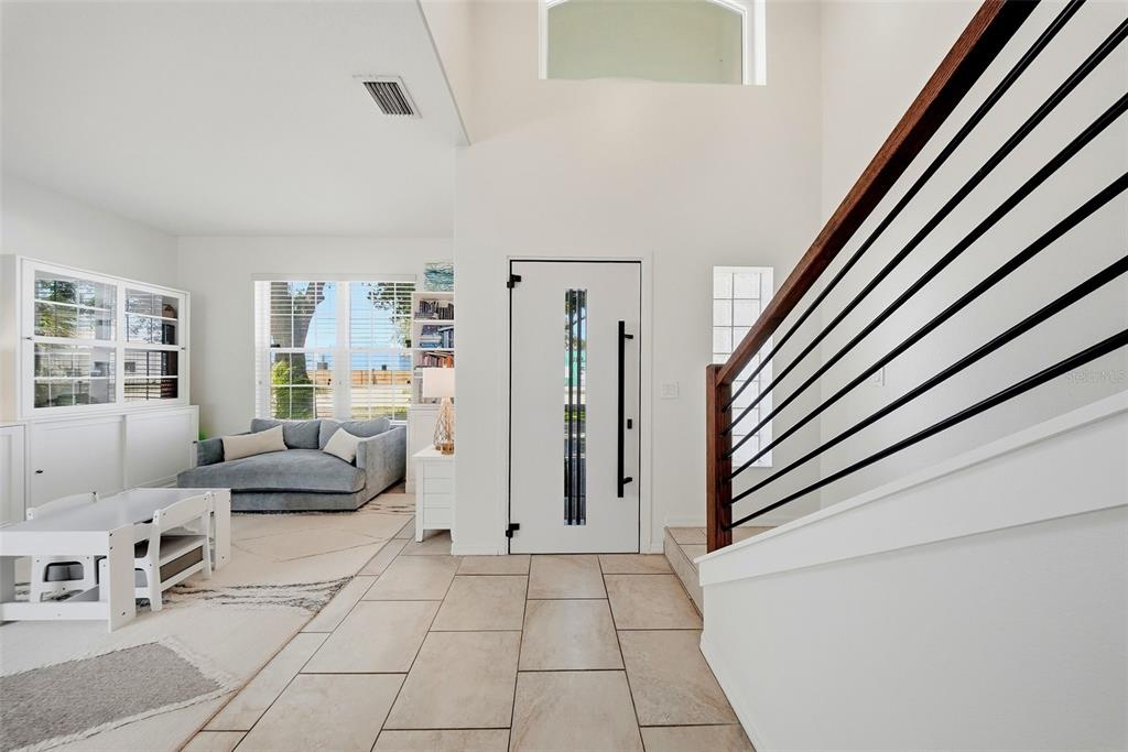 A bright entryway features tile flooring, a modern front door, and a staircase with railings — 236 15TH AVENUE SE, ST PETERSBURG, FL
