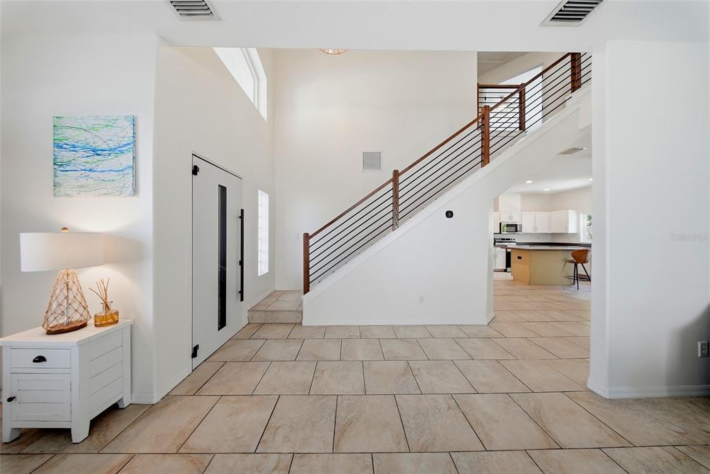 A bright foyer features tile flooring, a staircase with horizontal railings, and a white door — 236 15TH AVENUE SE, ST PETERSBURG, FL