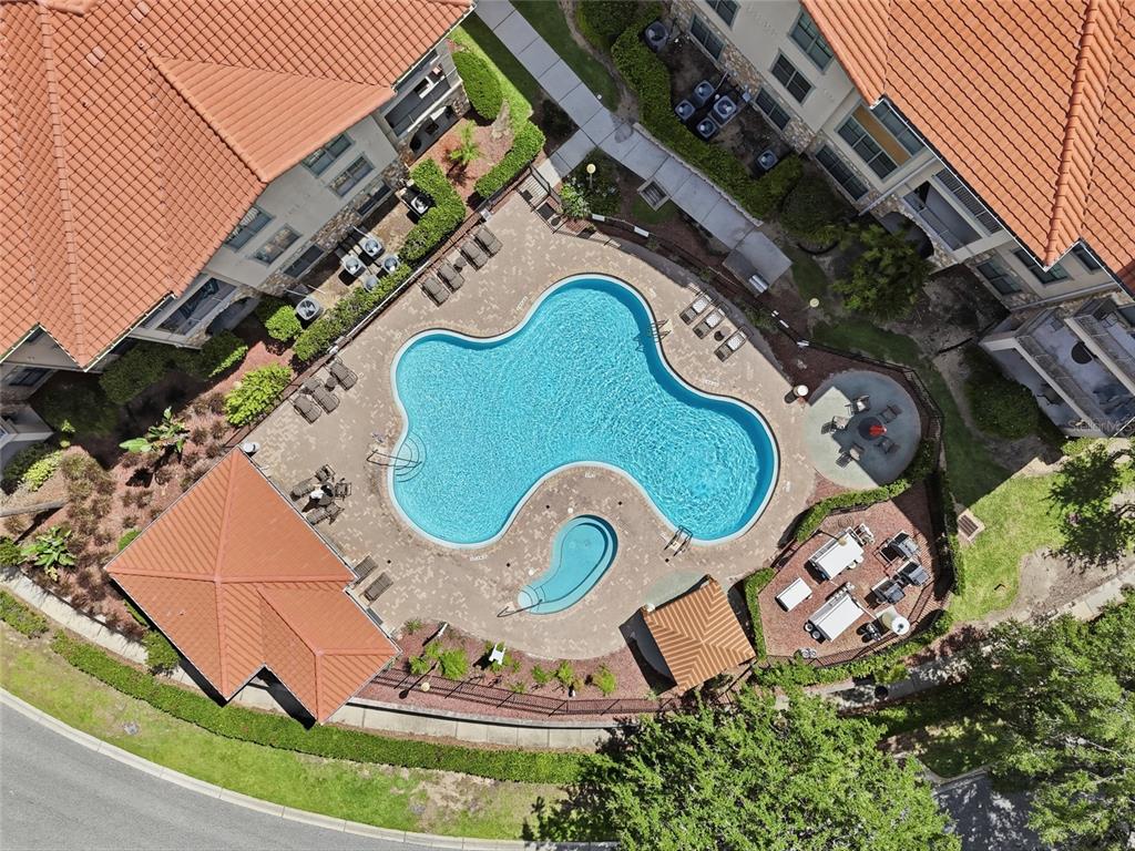 Aerial view of a community swimming pool with a spa and surrounding patio area — 901 CHARO PARKWAY UNIT 717, DAVENPORT, FL