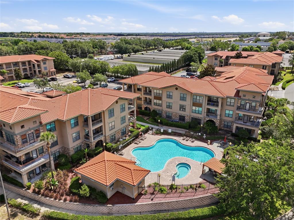 An aerial view shows a multi-story apartment complex with a swimming pool and hot tub — 901 CHARO PARKWAY UNIT 717, DAVENPORT, FL