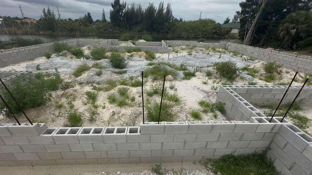 An unfinished concrete block foundation sits on a sandy lot with sparse vegetation — 15408 LAKELAND CIRCLE, PORT CHARLOTTE, FL