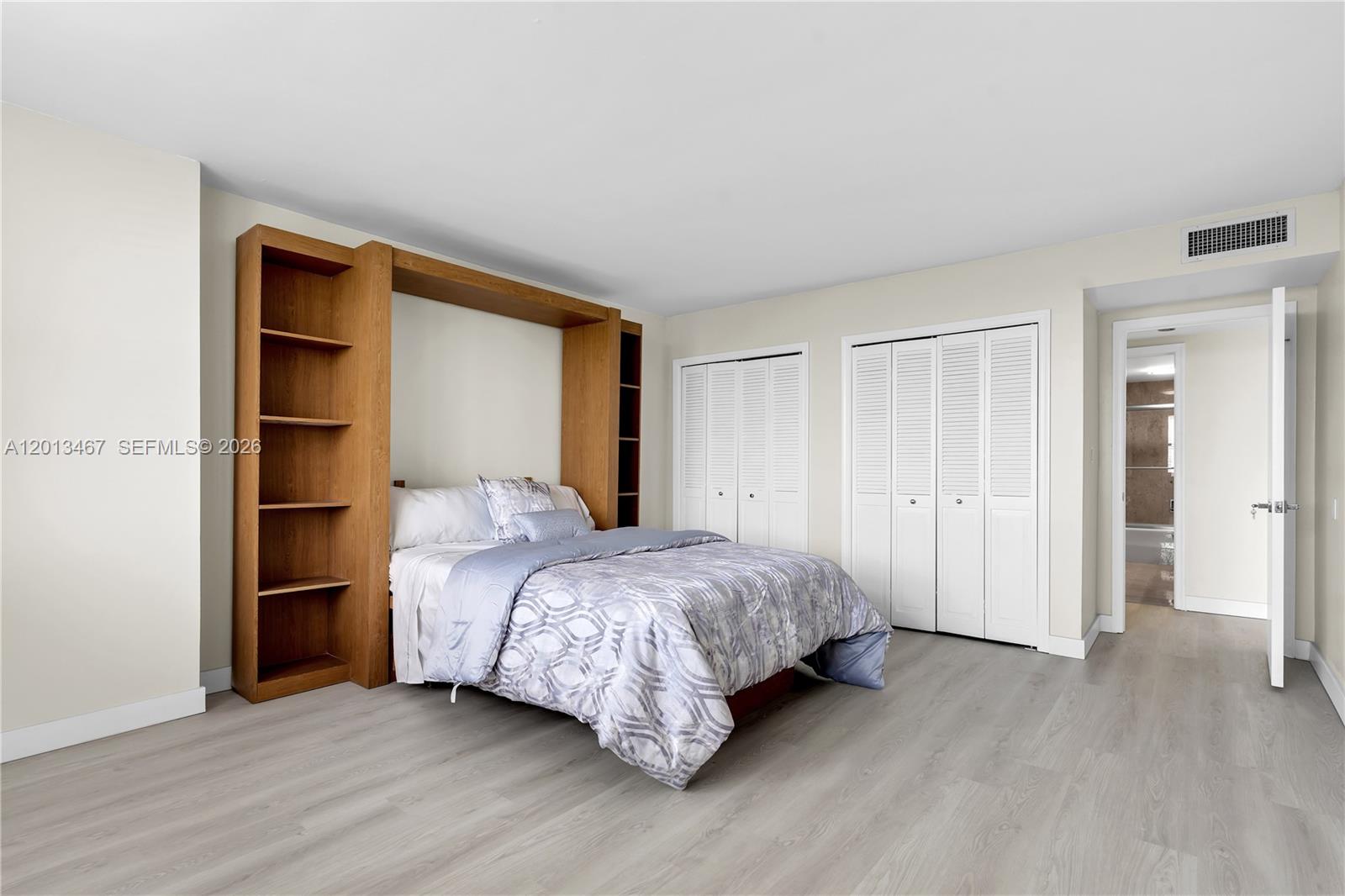 A bedroom features a wooden Murphy bed unit, white louvered closet doors, and light-colored flooring — 1800 NE 114th St # 601, Miami FL 33181, MIAMI, FL