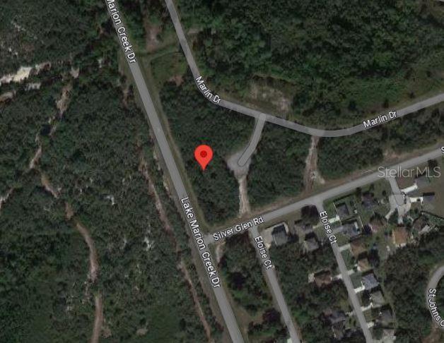 This is an aerial map view showing a vacant wooded lot near a residential street intersection — 609 MARLIN WAY, POINCIANA, FL