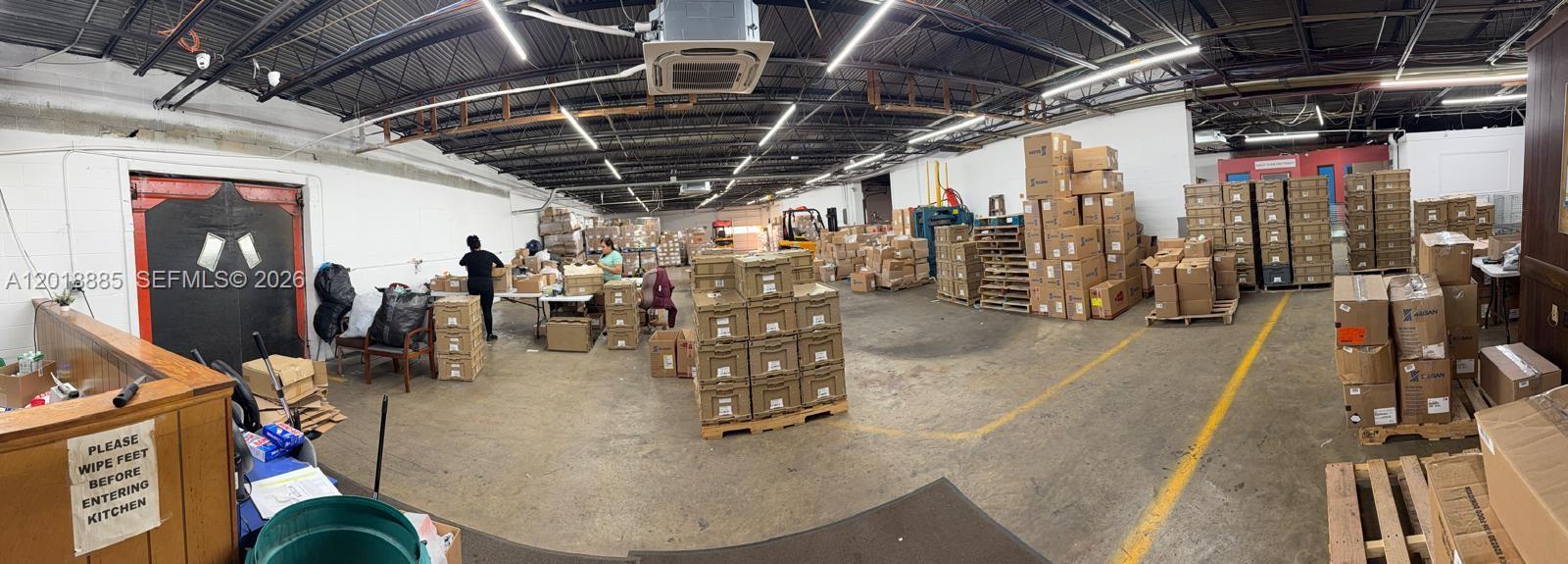 A large warehouse space features concrete floors, exposed ceilings, and numerous stacked cardboard shipping boxes — PARKLAND, FL