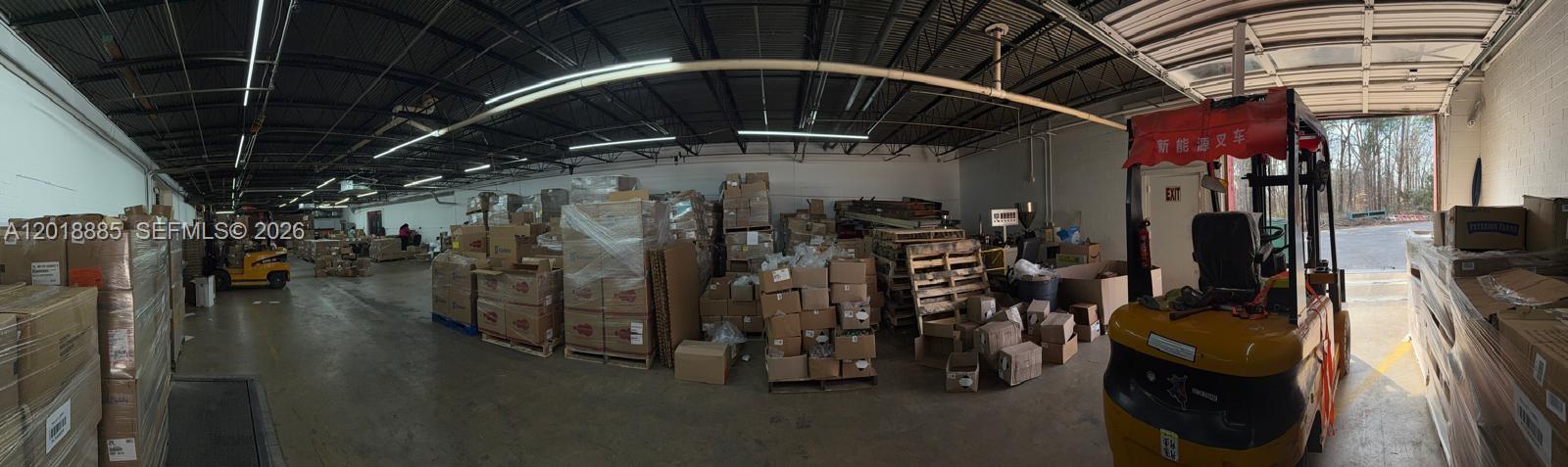 A wide-angle view of a warehouse interior featuring stacked cardboard boxes and a yellow forklift — PARKLAND, FL