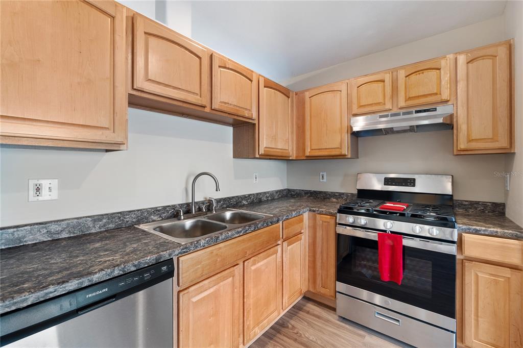 A kitchen with light wood cabinets, stainless steel appliances, and dark laminate countertops — 2917 WILSHIRE ROAD, CLERMONT, FL