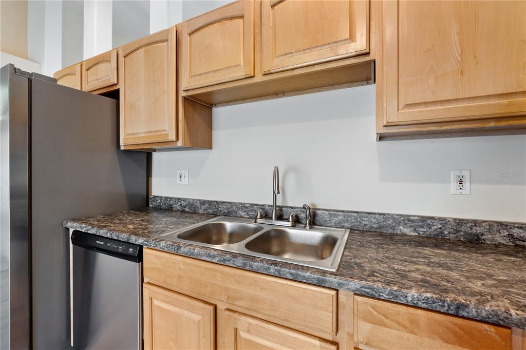 A kitchen features light wood cabinets, a stainless steel sink, and dark laminate countertops — 2917 WILSHIRE ROAD, CLERMONT, FL