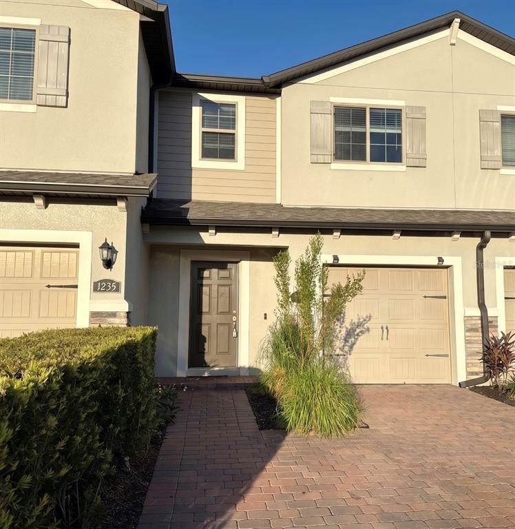 A two-story townhouse exterior features a paved driveway, a front door, and two garage doors — 1031 FLOWING TIDE DRIVE, ORLANDO, FL
