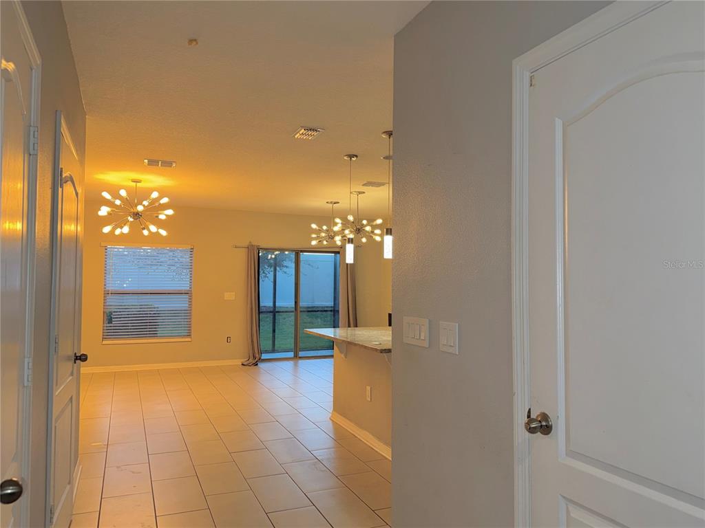 An interior view shows a tiled living area with modern light fixtures and sliding glass doors — 1031 FLOWING TIDE DRIVE, ORLANDO, FL