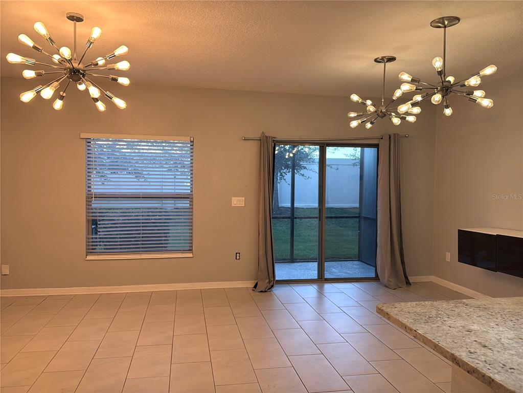A room with tile floors, two sputnik-style chandeliers, a window with blinds, and sliding doors — 1031 FLOWING TIDE DRIVE, ORLANDO, FL