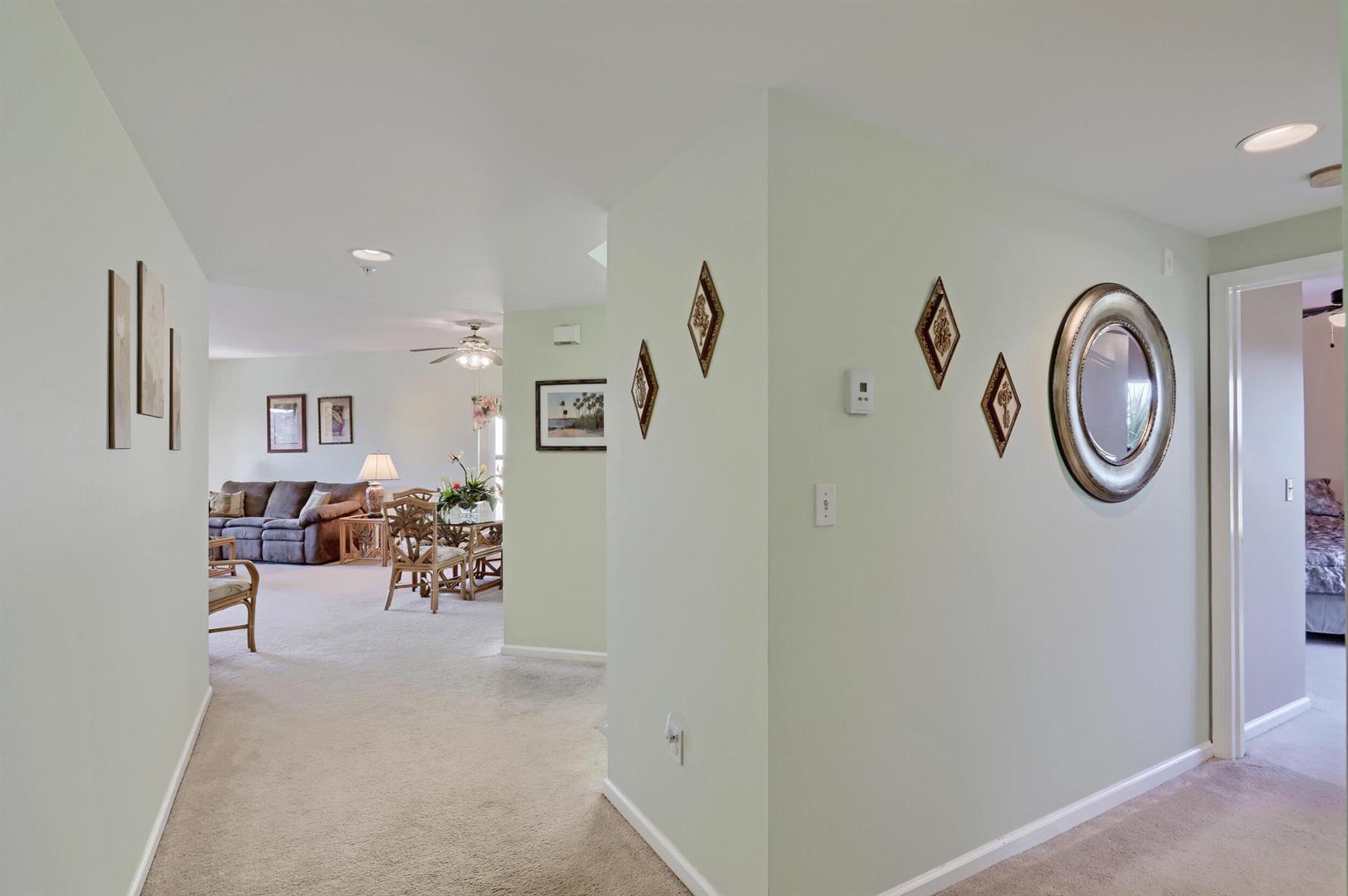 A hallway with light green walls leads to a living and dining area with carpet — 800 Uno Lago Drive # 305, Juno Beach FL 33408, JUNO BEACH, FL