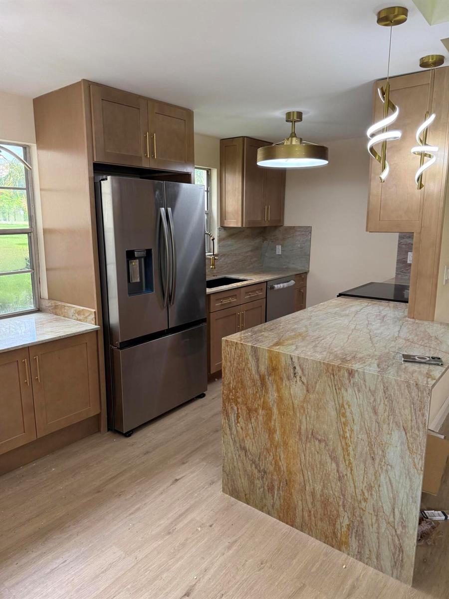A kitchen features light wood cabinets, stainless steel appliances, and a stone-topped island — 47 Preston B # 47, Boca Raton FL 33434, BOCA RATON, FL