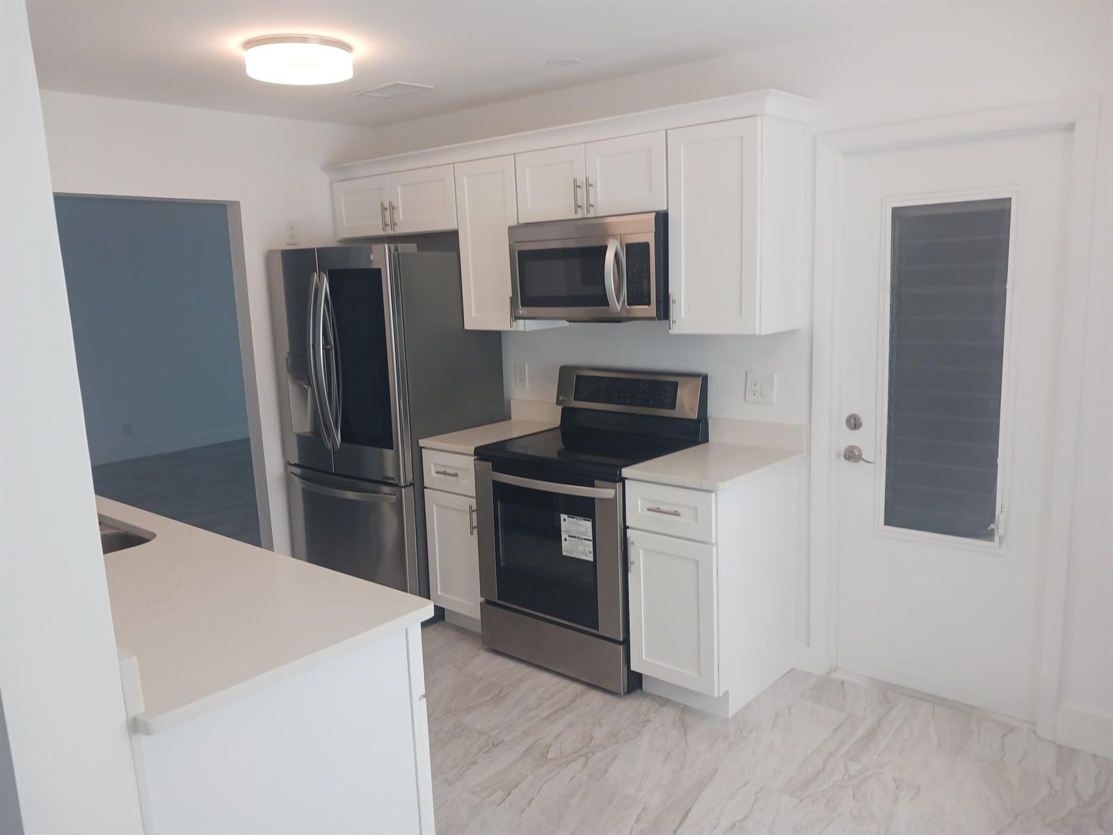 A kitchen features white cabinets, stainless steel appliances, and light-colored countertops — 1590 SW 14th Avenue, Boynton Beach FL 33426, BOYNTON BEACH, FL