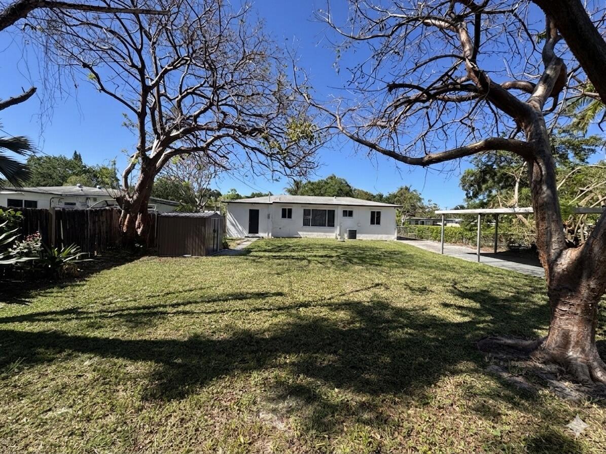 A white single-story house sits at the end of a large, grassy backyard with trees — 2648 Washington Street, Hollywood FL 33020, HOLLYWOOD, FL