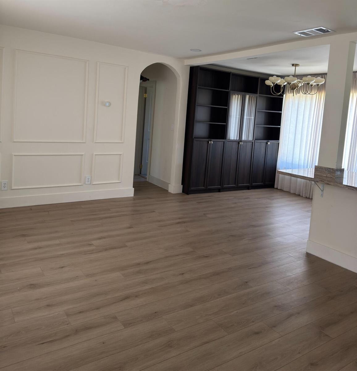 An open living area features light wood flooring, white wainscoting, and a dark built-in bookshelf — 2648 Washington Street, Hollywood FL 33020, HOLLYWOOD, FL