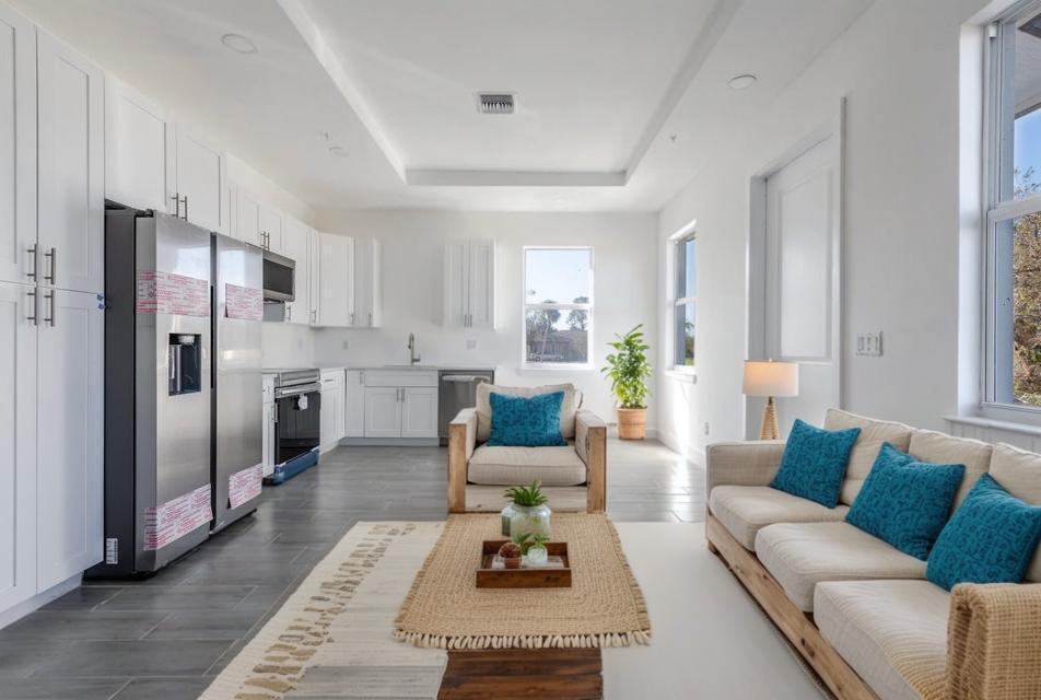 A bright, open-concept kitchen and living area featuring white cabinetry, stainless appliances, and tile flooring — 246 Rotonda Blvd Boulevard W # B, FL 33947, FL