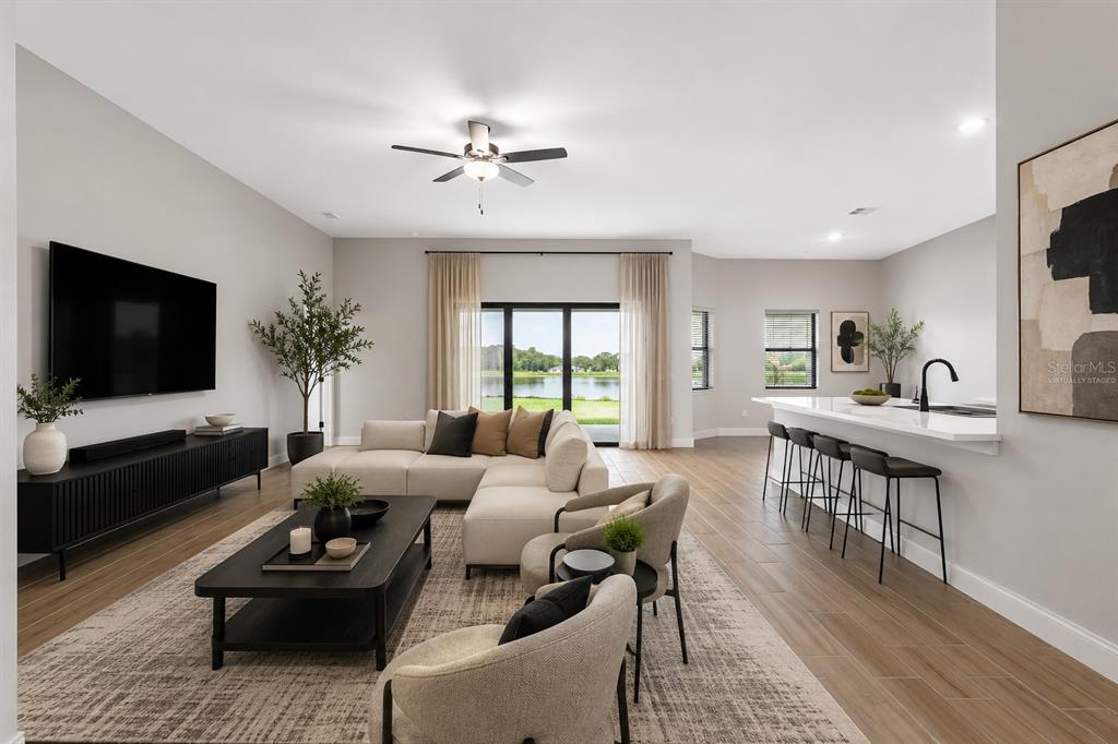 A modern living room with a sectional sofa, coffee table, and kitchen island overlooking a lake — 13483 LAKE GALLAGHER DRIVE, DOVER, FL