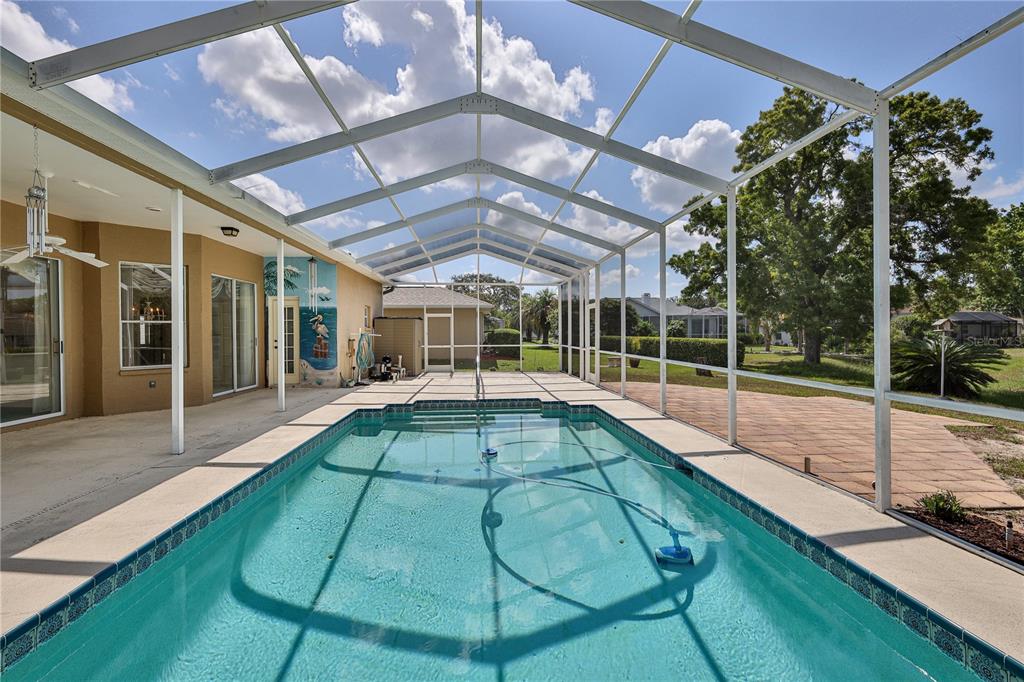 A rectangular swimming pool sits inside a screened-in lanai with a concrete patio — 10376 HENDERSON STREET, SPRING HILL, FL