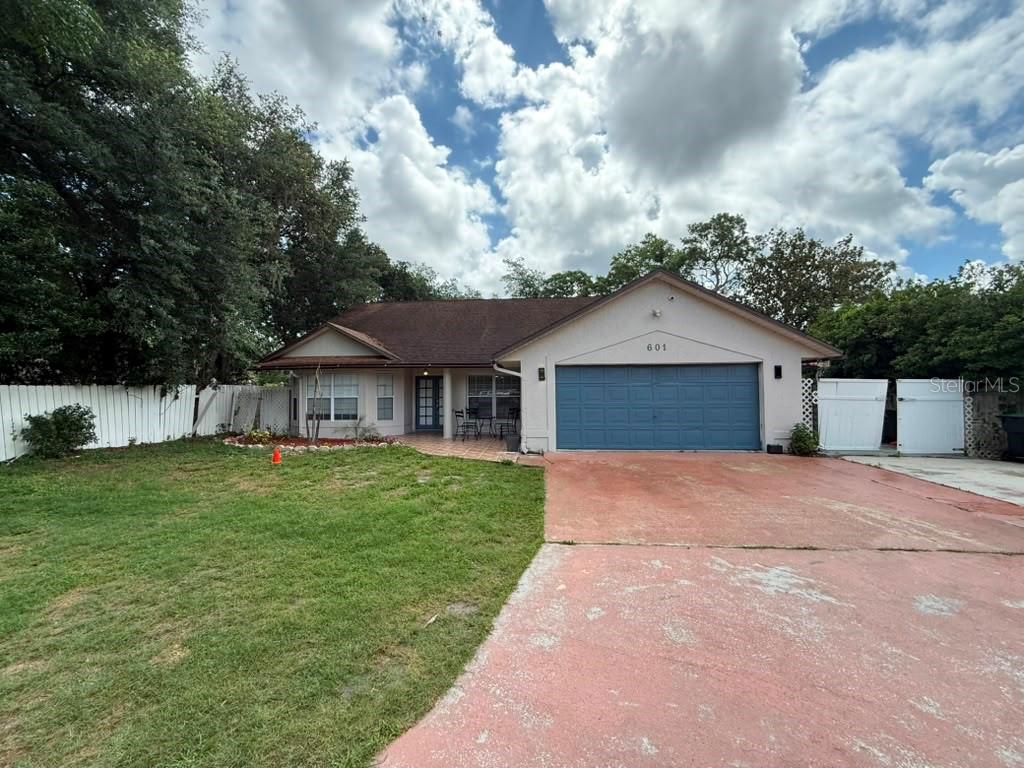 A single-story house with a blue garage door, a red driveway, and a white fence — 601 S DEAN ROAD, ORLANDO, FL