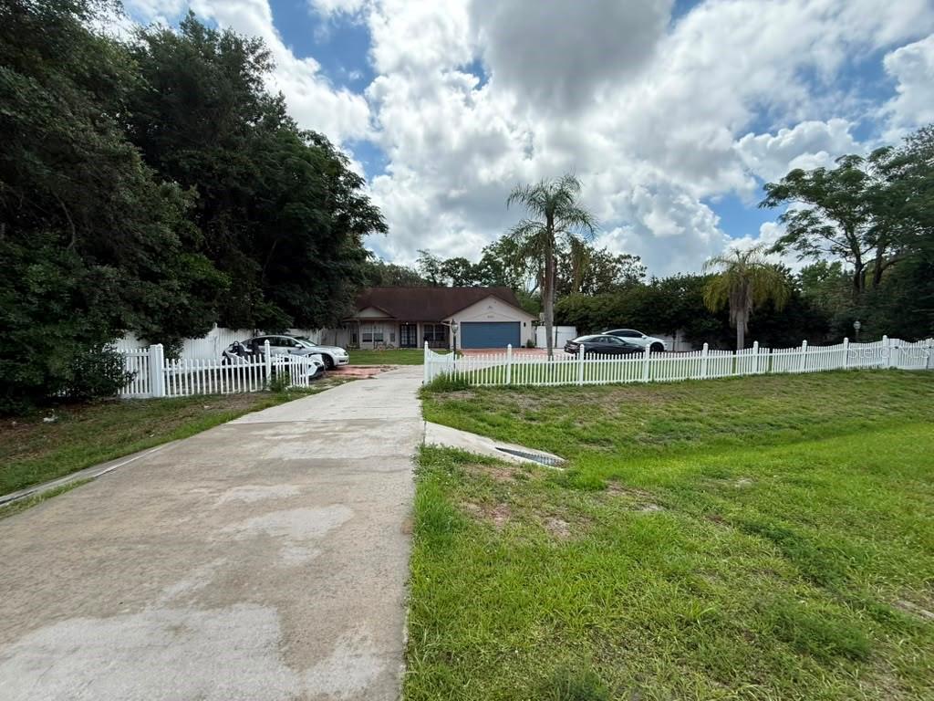 A single-story house with a blue garage door sits behind a white picket fence — 601 S DEAN ROAD, ORLANDO, FL