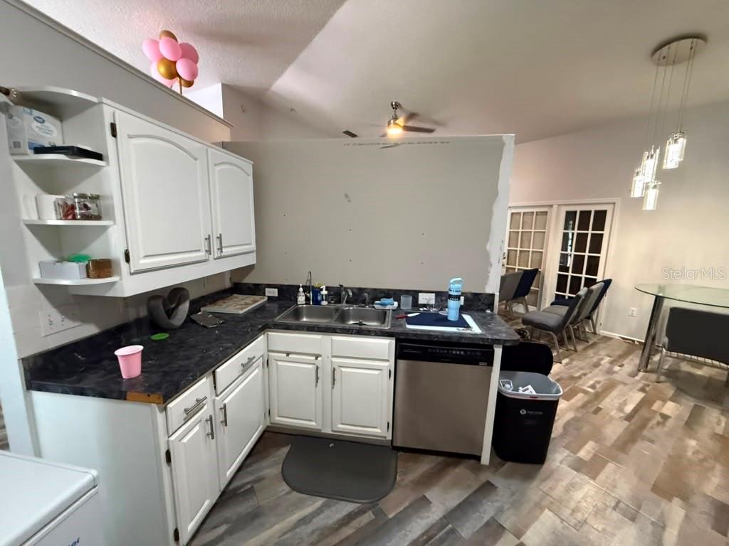 A kitchen features white cabinets, dark countertops, a stainless steel dishwasher, and unfinished drywall — 601 S DEAN ROAD, ORLANDO, FL