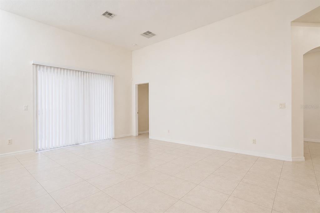 An empty room with high ceilings, tile flooring, and a sliding glass door — 2509 LAUREL BLOSSOM CIRCLE, OCOEE, FL