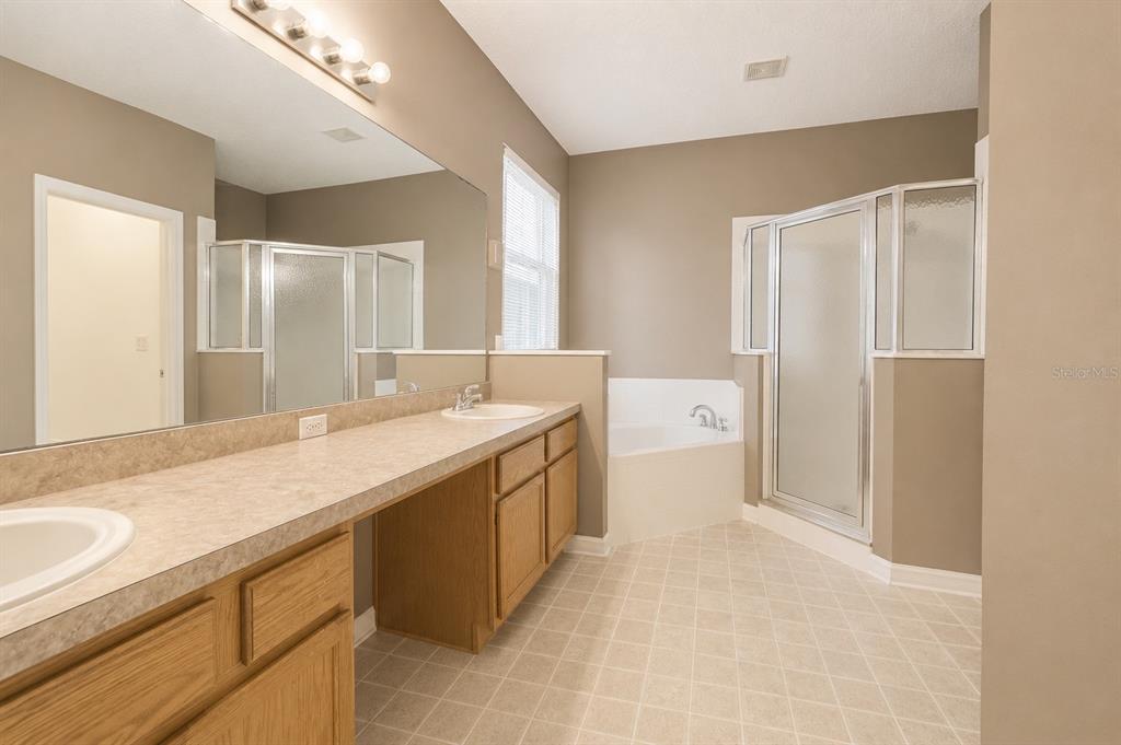 A bathroom features a double vanity, a corner soaking tub, and a separate glass-enclosed shower — 2509 LAUREL BLOSSOM CIRCLE, OCOEE, FL