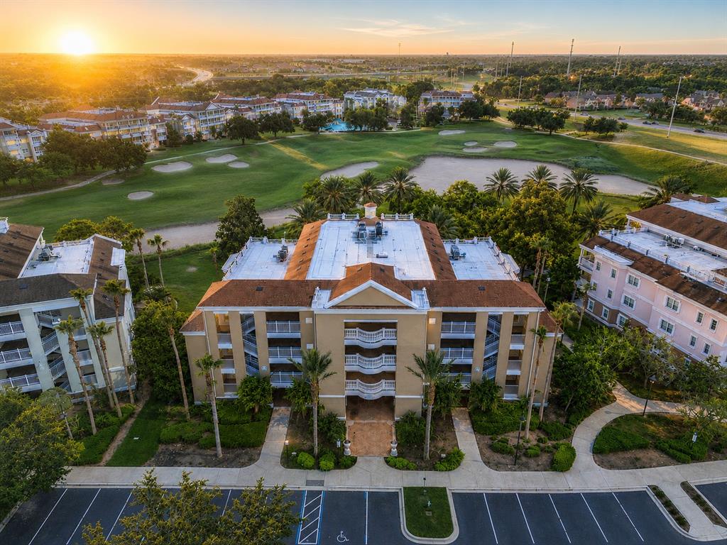 An aerial view shows a multi-story apartment building with a parking lot and golf course — 1106 SUNSET VIEW CIRCLE UNIT 304, REUNION, FL