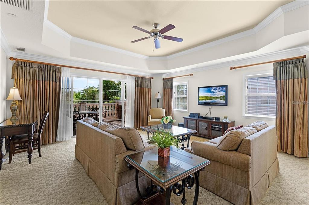 A living room features a tray ceiling, beige sofas, a glass coffee table, and sliding doors — 1106 SUNSET VIEW CIRCLE UNIT 304, REUNION, FL