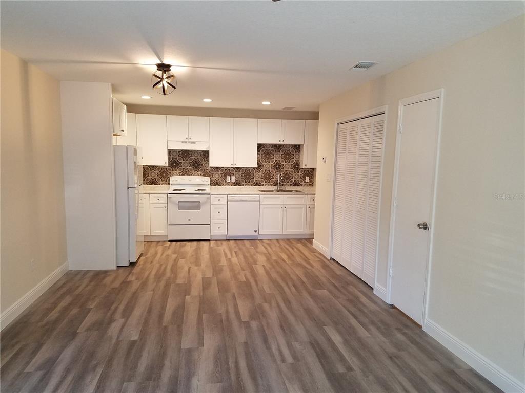 A kitchen with white cabinets, patterned backsplash, and wood-look flooring in an open-concept room — 505 BOXELDER AVENUE, ALTAMONTE SPRINGS, FL